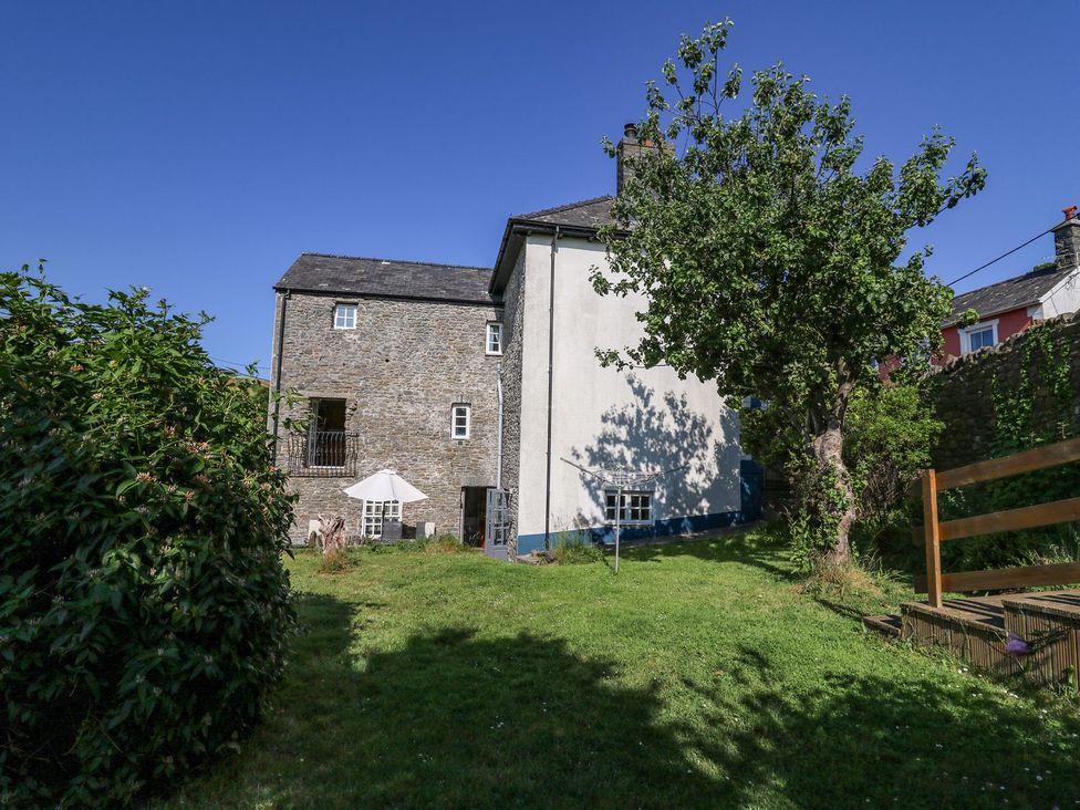 A garden area with a building and a tree at Dewi Villa Apartment in Aberaeron