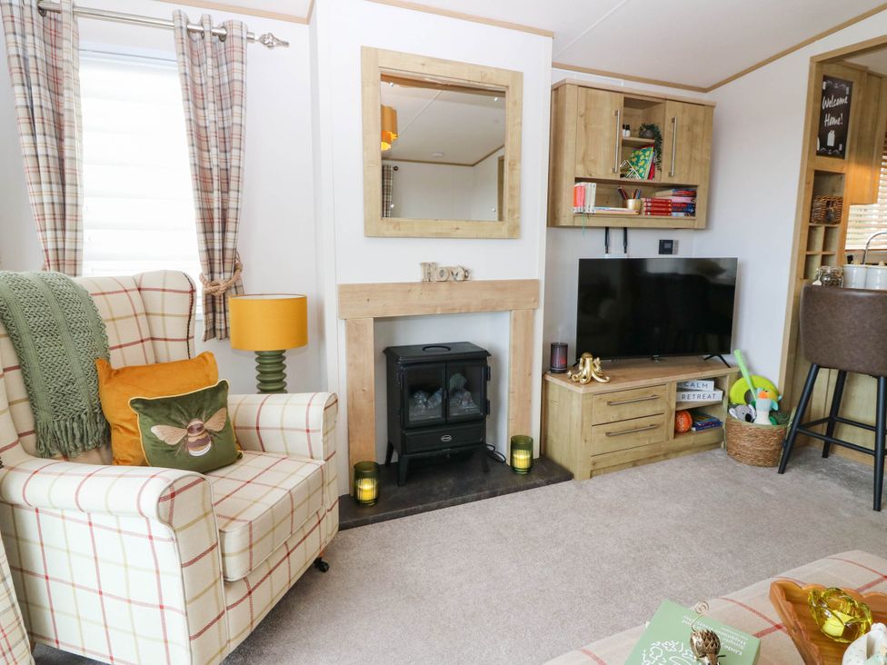 A living room with an armchair, fireplace and television at The Manor’s Retreat Dunbar