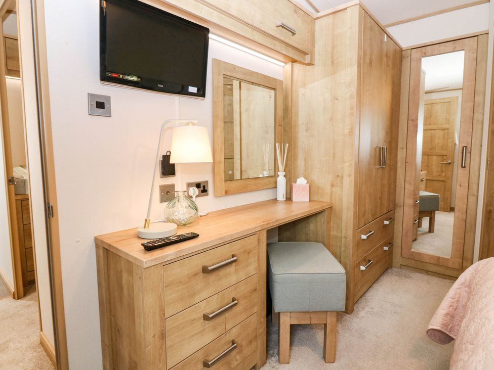 A bedroom with a dresser, mirror, and a stool at The Manor’s Retreat in Dunbar