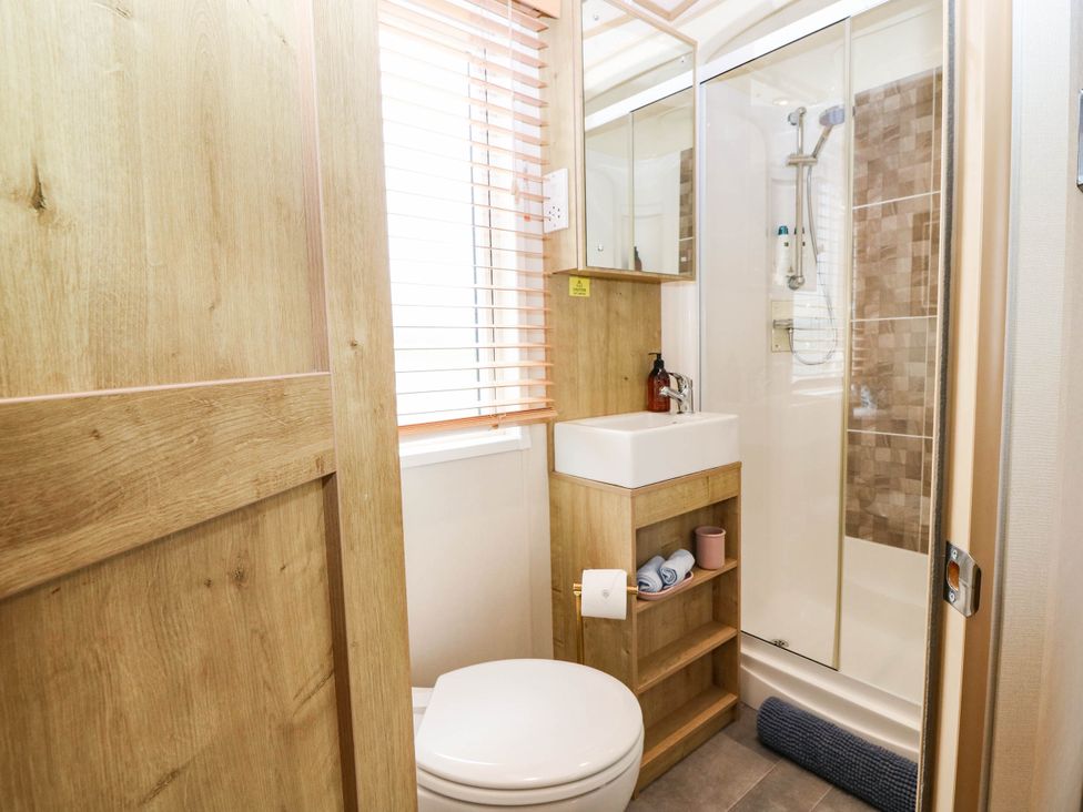 A bathroom with a toilet, sink, shower, and storage at The Manor’s Retreat in Dunbar