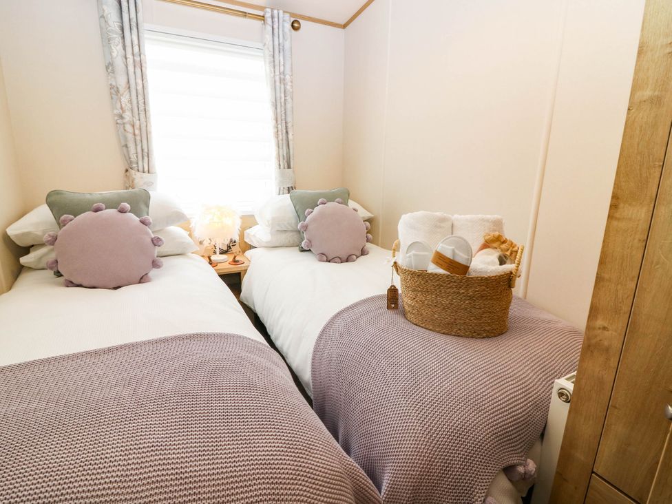 A bedroom with twin beds and a basket of towels at The Manor’s Retreat in Dunbar