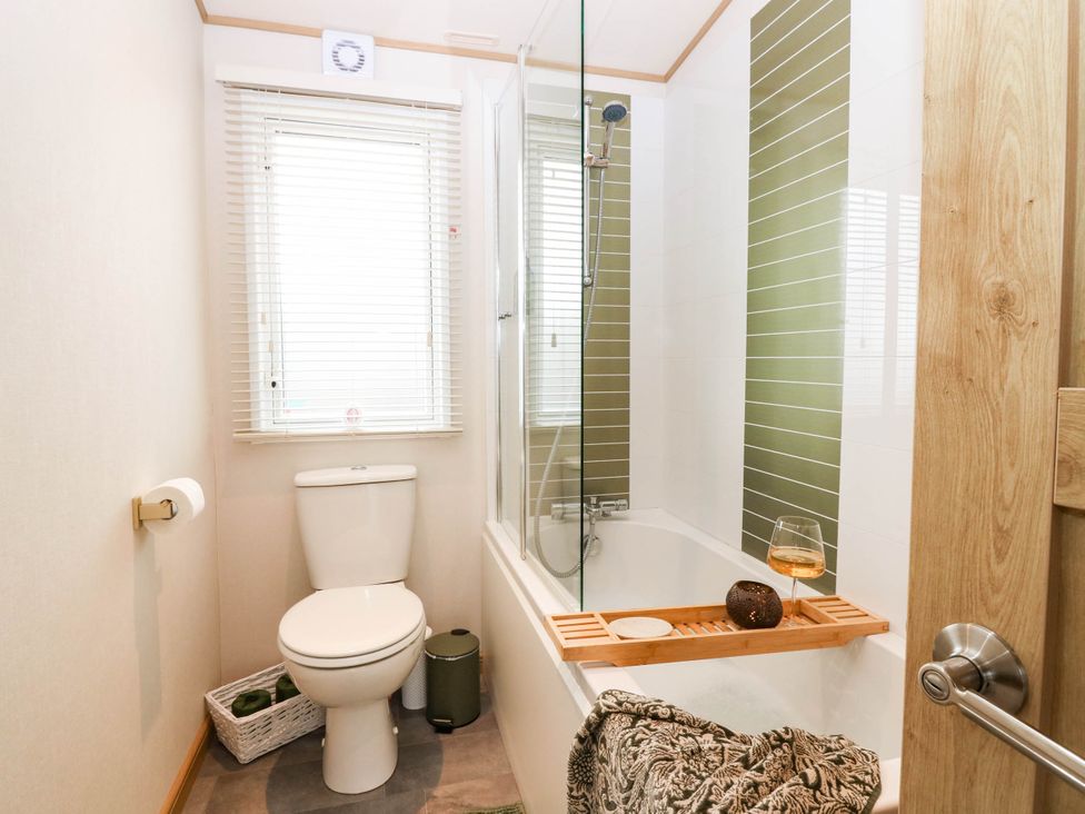 A bathroom with a toilet and a shower over a bathtub at The Manor’s Retreat in Dunbar
