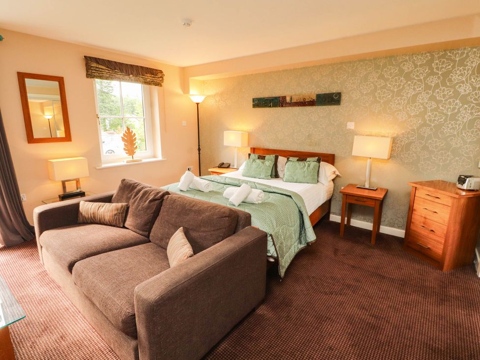 A bedroom with a bed and sofa at Ullswater Apartment- No 15
