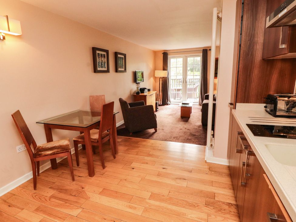 A dining area and living room with a sofa and television at Ullswater Apartment- No 15