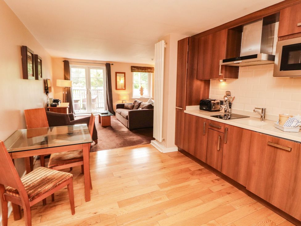 A living room and kitchen area with a dining table and chairs at Ullswater Apartment- No 15