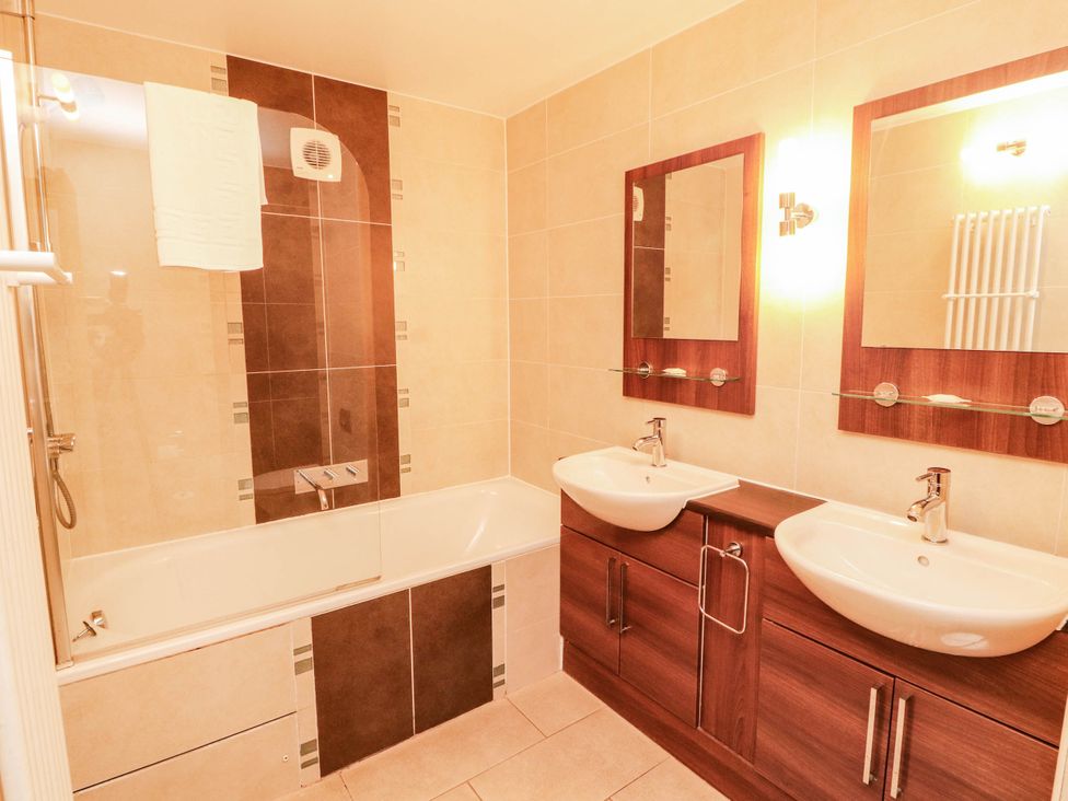 A bathroom with bathtub, sinks, and mirrors at Ullswater Apartment- No 15