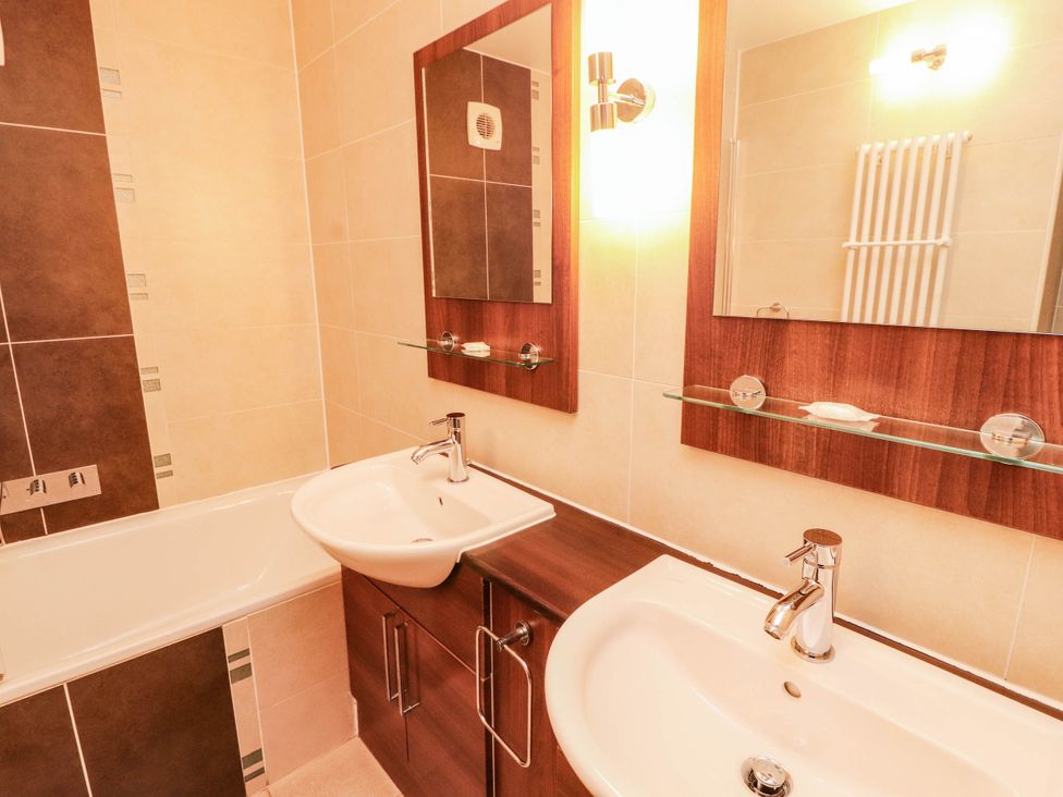 A bathroom with a bathtub and two sinks at Ullswater Apartment- No 15