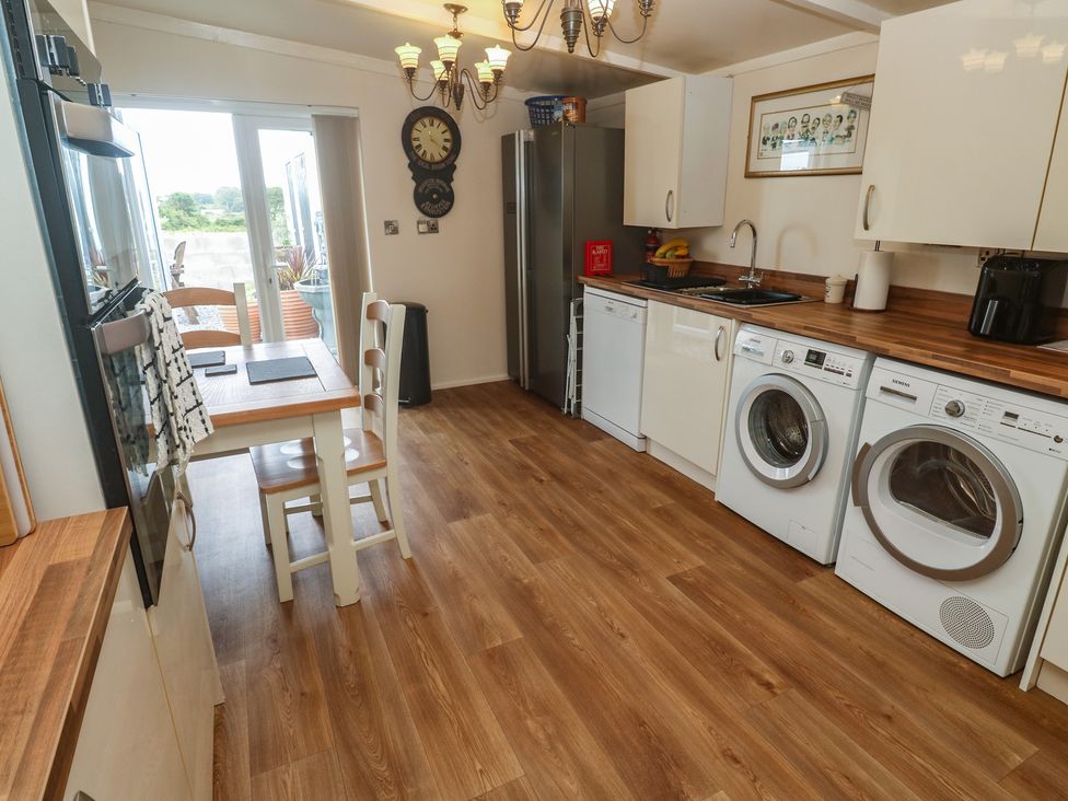 A kitchen with appliances and a dining table at The Hideaway at Monterey in Helston