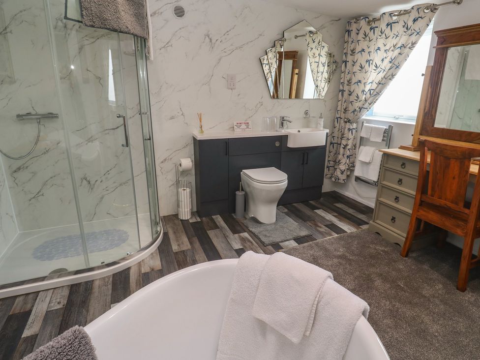 A bathroom with shower, bathtub, sink, and toilet at The Hideaway at Monterey in Helston