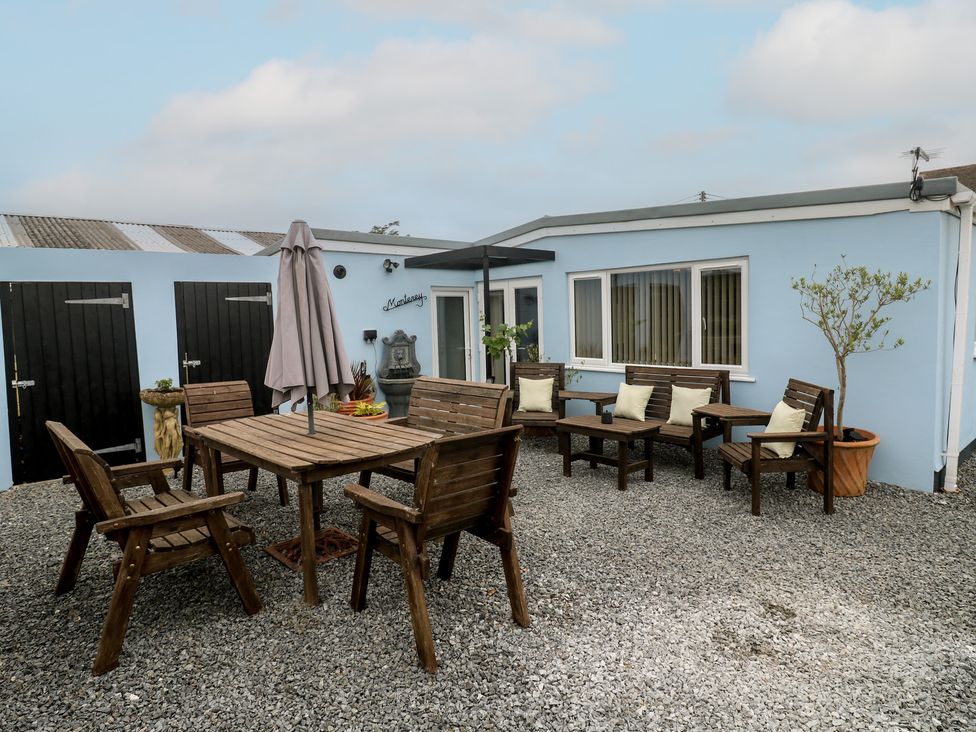 An outdoor seating area with wooden furniture at The Hideaway at Monterey in Helston
