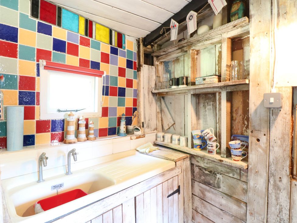 A kitchen with a sink and colorful tiled wall at Ladies of Bolton in Horsford