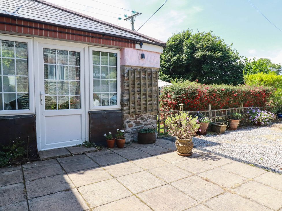 A garden with a stone wall and potted plants at The Jingle House in Tregony