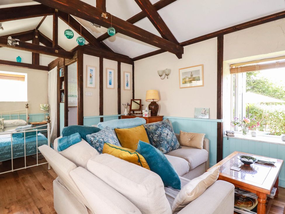 A living room with a sofa and bed at The Jingle House in Tregony