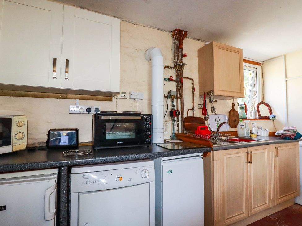 A kitchen with appliances and cabinets at The Jingle House in Tregony