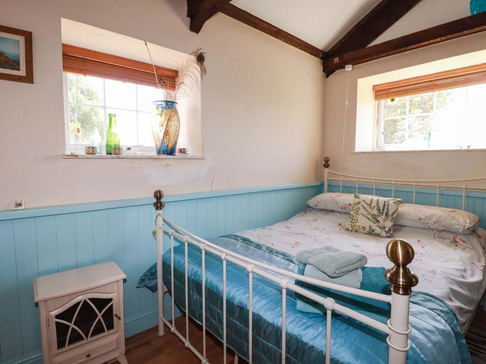 A bedroom with a bed and bedside table at The Jingle House in Tregony