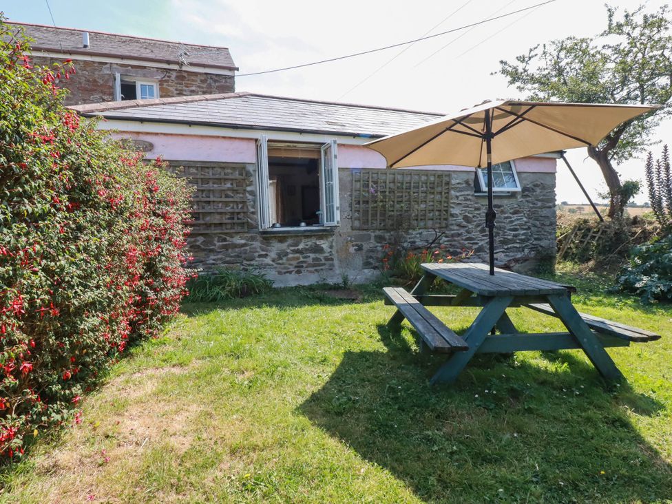 A garden with a picnic table and an umbrella at The Jingle House in Tregony