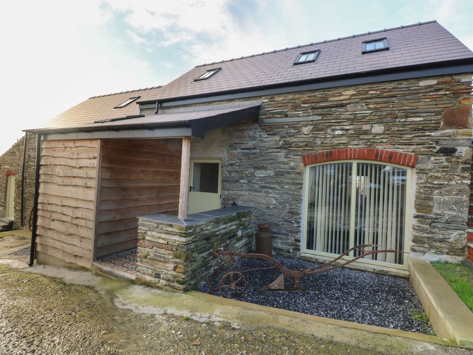 An outdoor view of a stone building with a wooden structure at The Cartbarn at Cadwgan Farm near Whitland