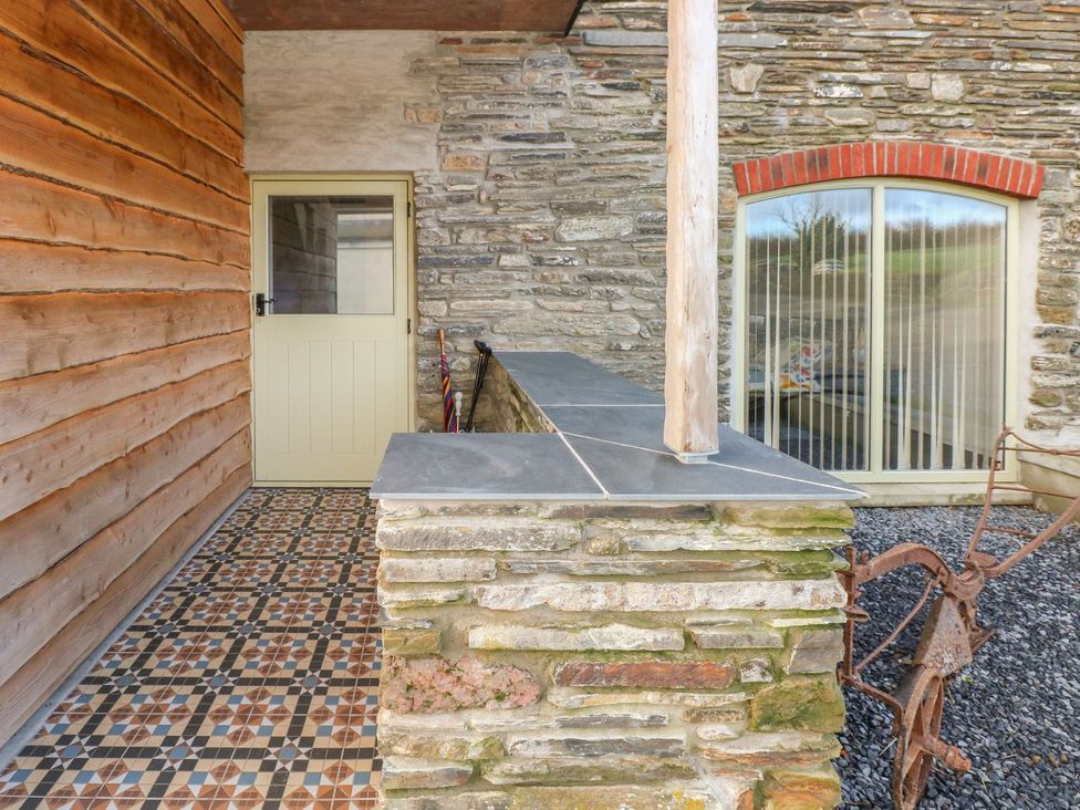 An outdoor entrance with stone wall and tiled flooring at The Cartbarn at Cadwgan Farm near Whitland