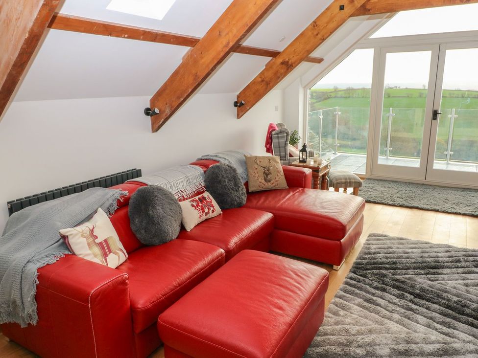 A living room with a red sofa and glass door at The Cartbarn at Cadwgan Farm near Whitland