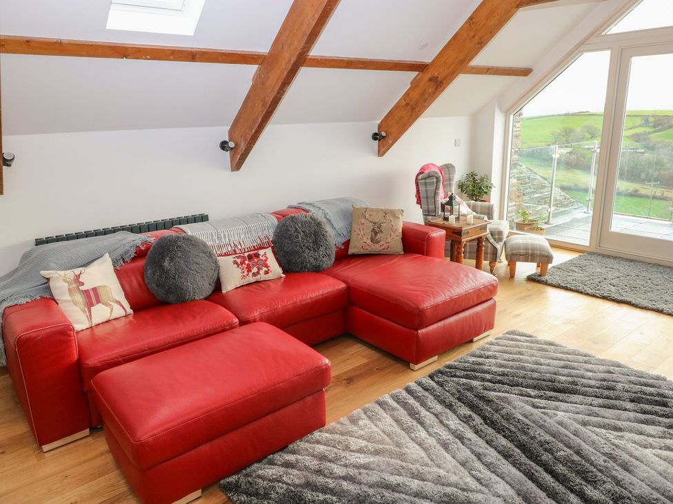 A living room with a red sofa and large window at The Cartbarn at Cadwgan Farm near Whitland