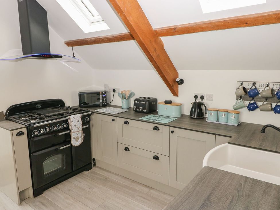 A kitchen with a stove, microwave, toaster, and sink at The Cartbarn at Cadwgan Farm near Whitland