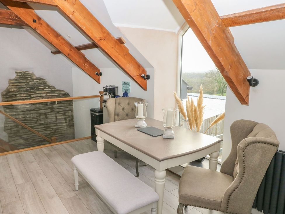 A loft area with a table and chairs at The Cartbarn at Cadwgan Farm near Whitland