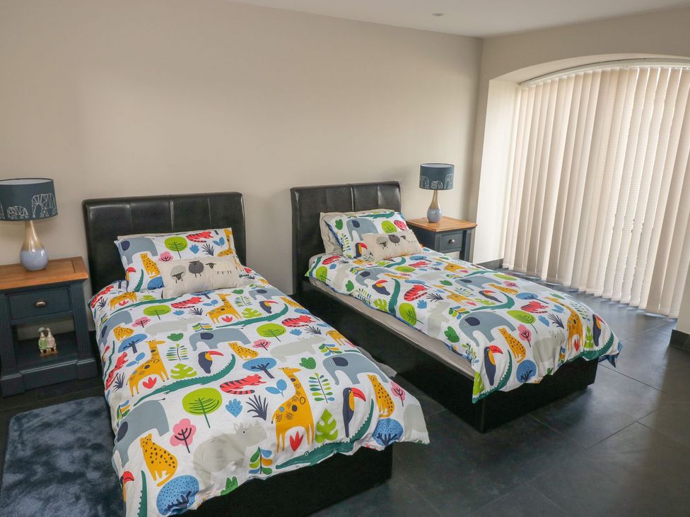 A bedroom with twin beds and nightstands at The Cartbarn at Cadwgan Farm near Whitland