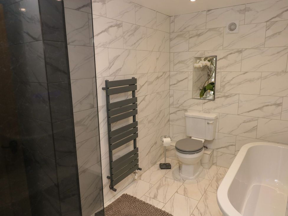 A bathroom with a shower, toilet, bathtub and towel warmer at The Cartbarn at Cadwgan Farm near Whitland