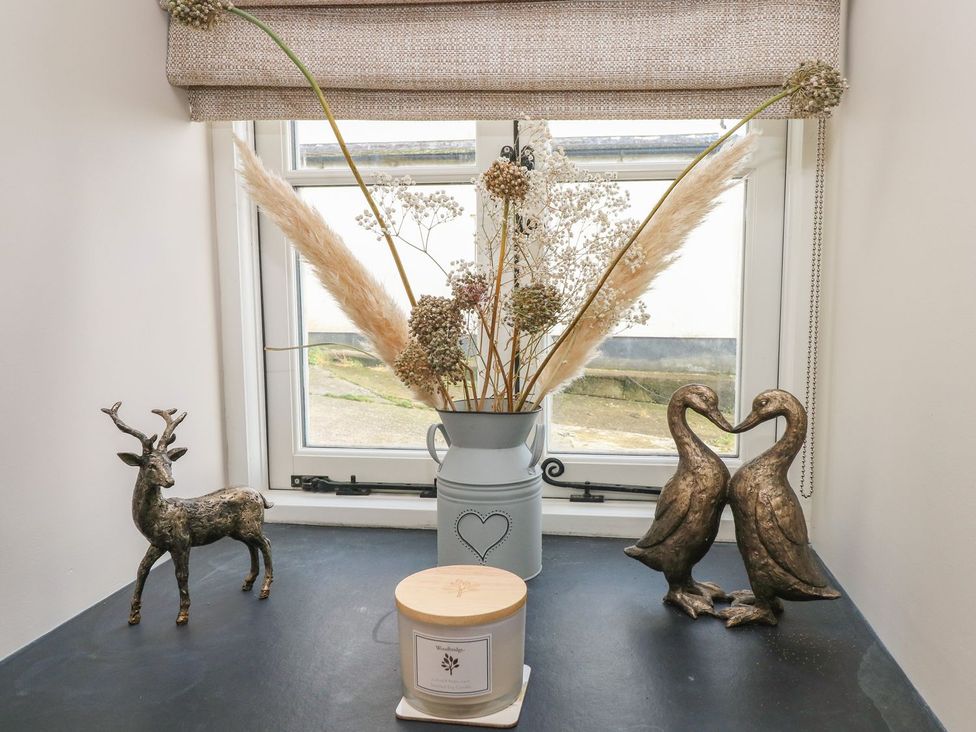 A window with decorative items including plants and figures at The Cartbarn at Cadwgan Farm near Whitland