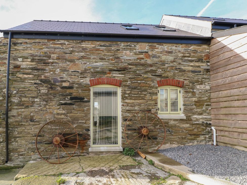 An exterior view of a stone wall with windows and wheels at The Cartbarn at Cadwgan Farm near Whitland