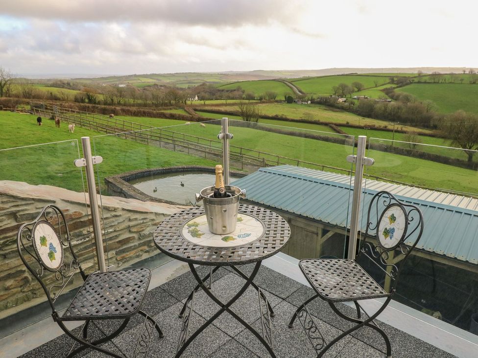 An outdoor seating area with a table and chairs overlooking the countryside at The Cartbarn at Cadwgan Farm near Whitland