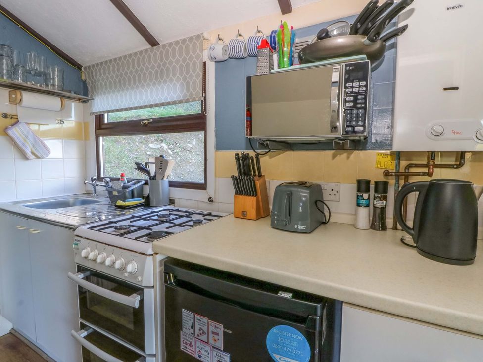 A kitchen with a gas stove, microwave, and sink at Captain's Cabin in Clarach Bay near Aberystwyth