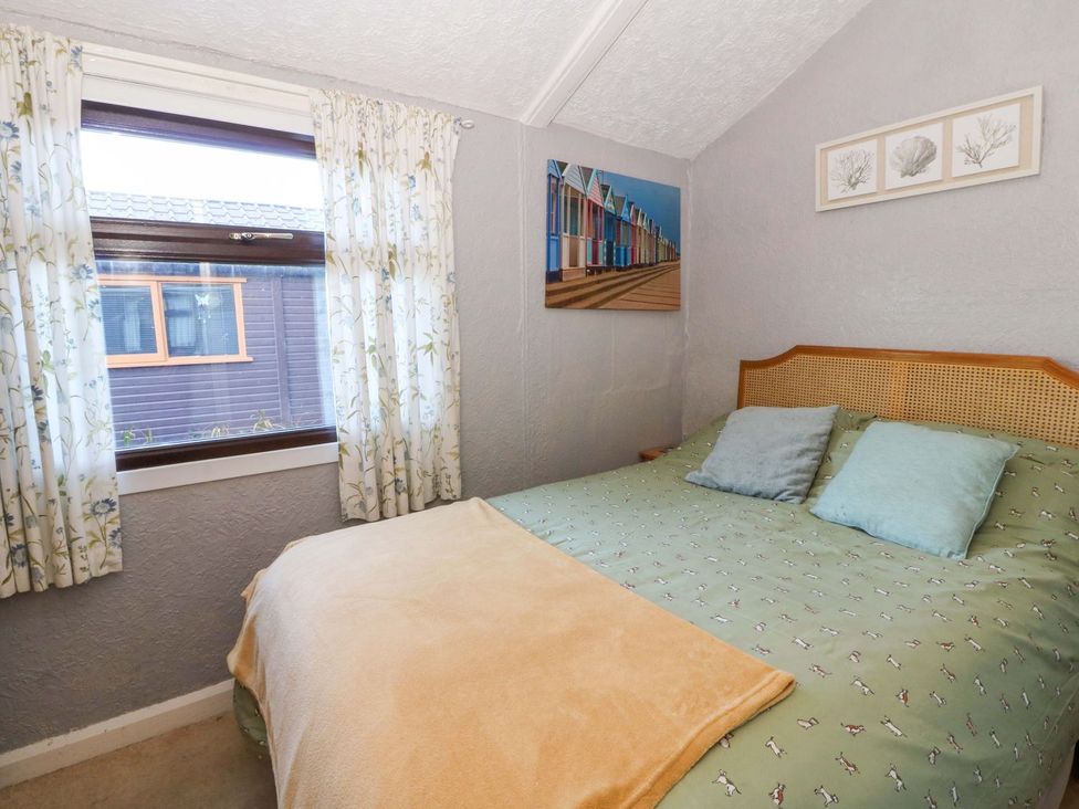 A bedroom with a bed and window at Captain's Cabin in Clarach Bay near Aberystwyth