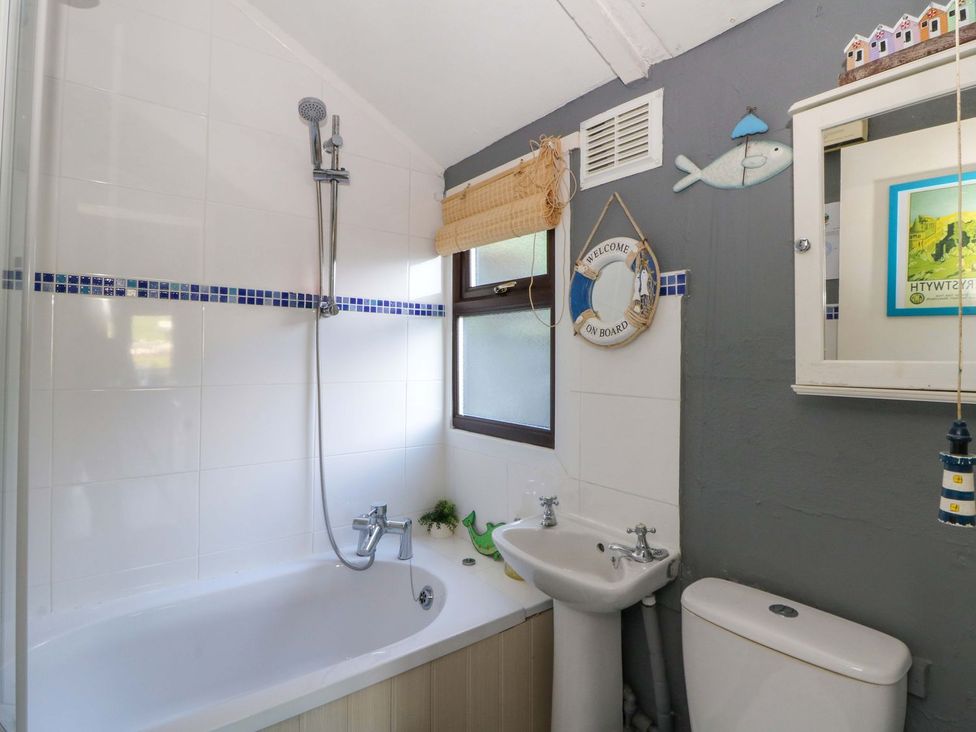 A bathroom with a bathtub, sink, shower, and toilet at Captain's Cabin in Clarach Bay near Aberystwyth