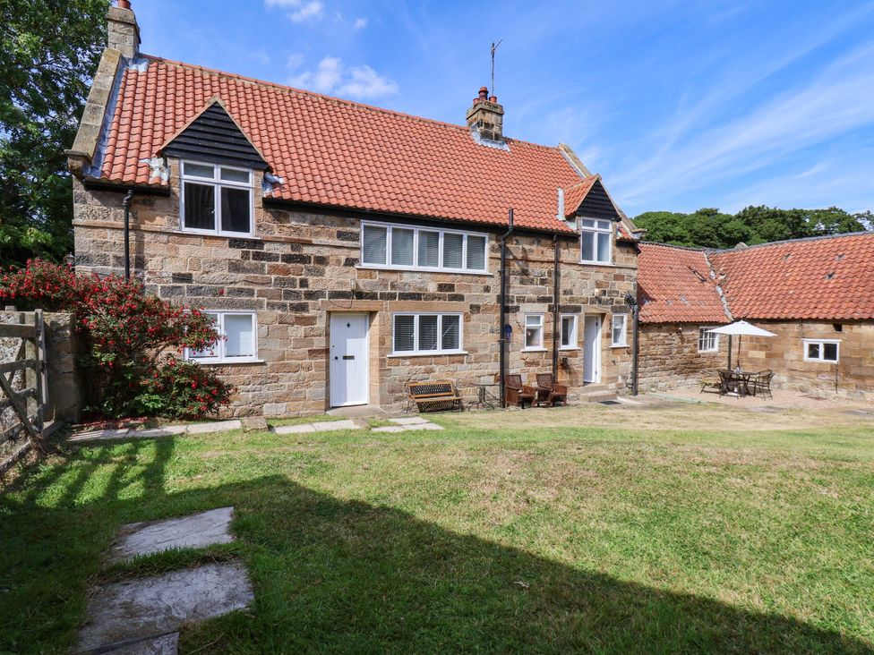 A house with benches and tables in the garden at Farmhouse in Whitby
