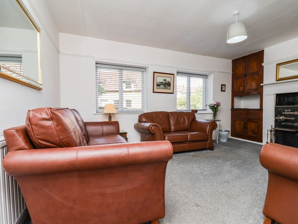 A living room with leather sofas and a lamp at Farmhouse in Whitby
