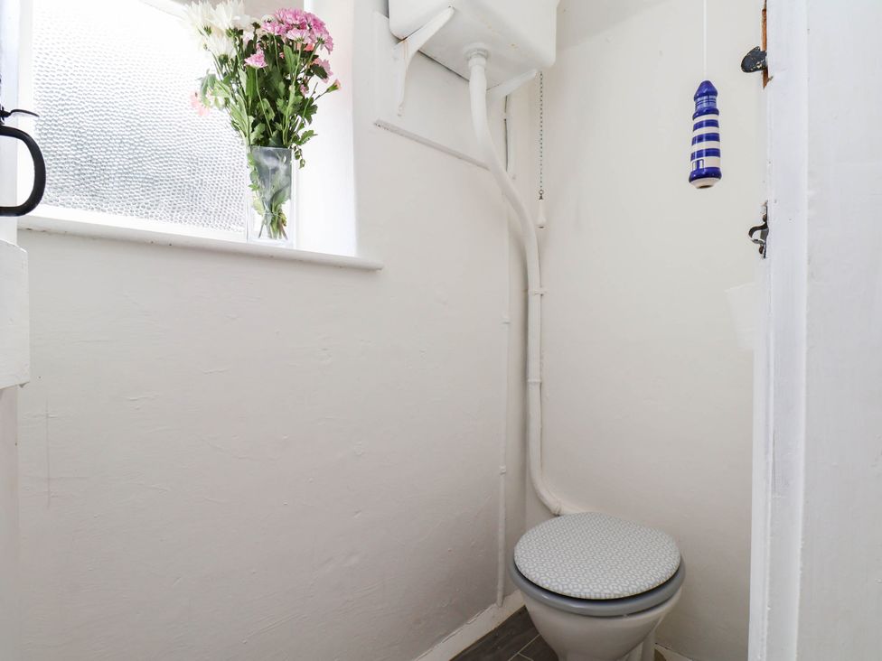 A bathroom with a toilet and a vase of flowers at the Farmhouse in Whitby