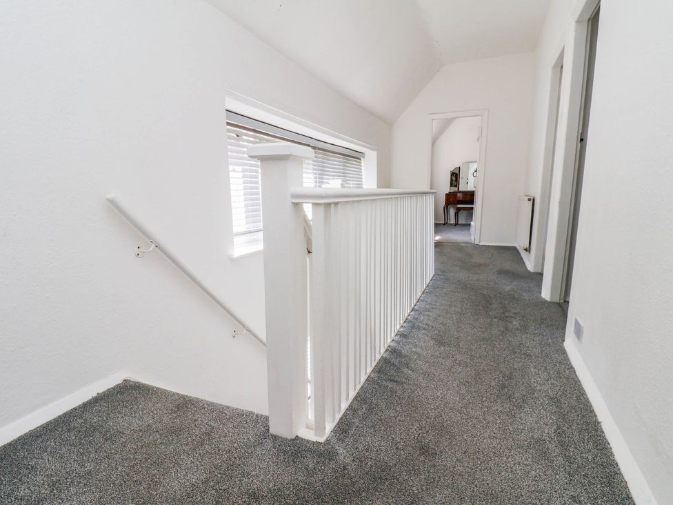 A hallway with stairs, railing, and windows at the Farmhouse in Whitby