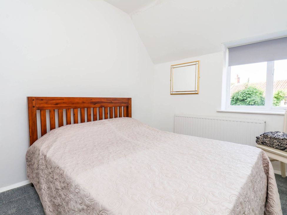 A bedroom with a wooden bed and window at Farmhouse in Whitby