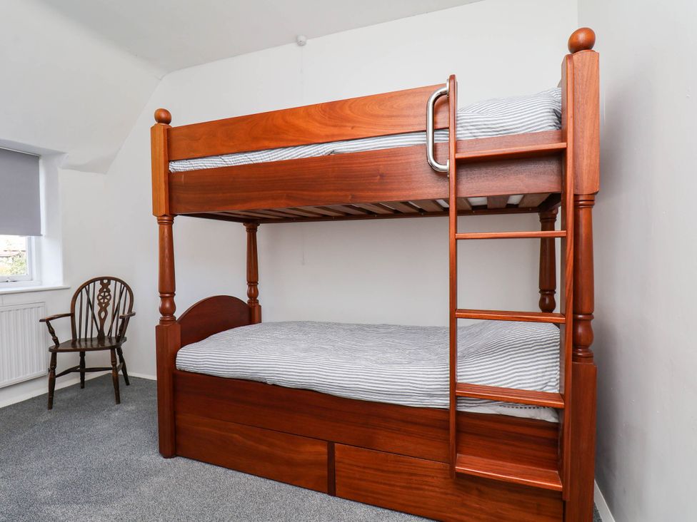 A bedroom with a bunk bed and chair at Farmhouse in Whitby