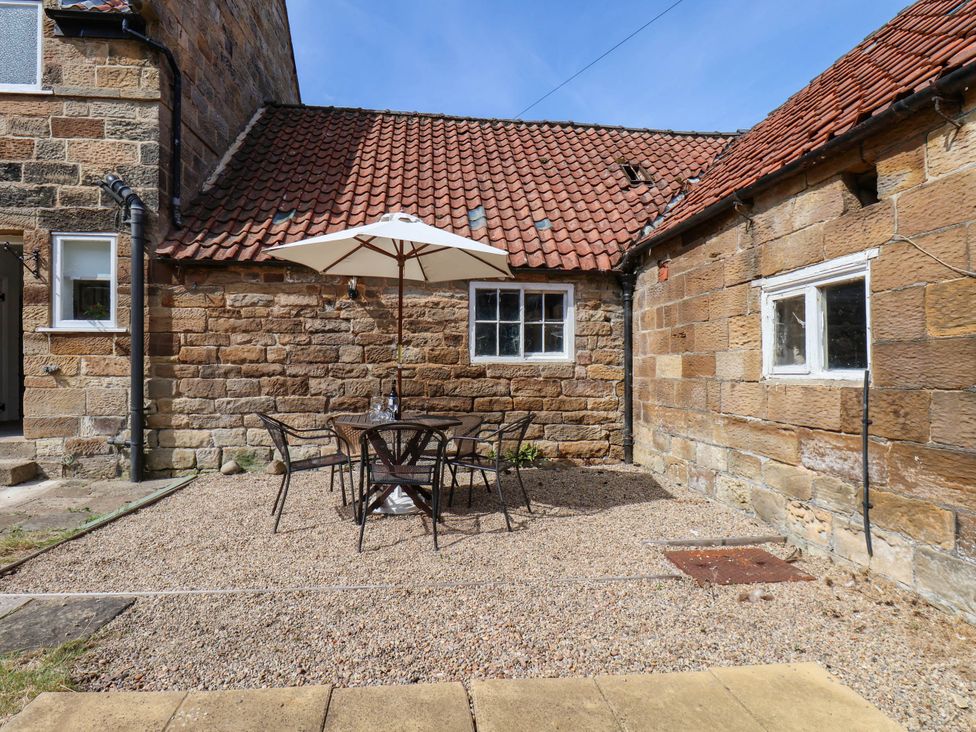 An outdoor area with a table and chairs under an umbrella at the Farmhouse in Whitby