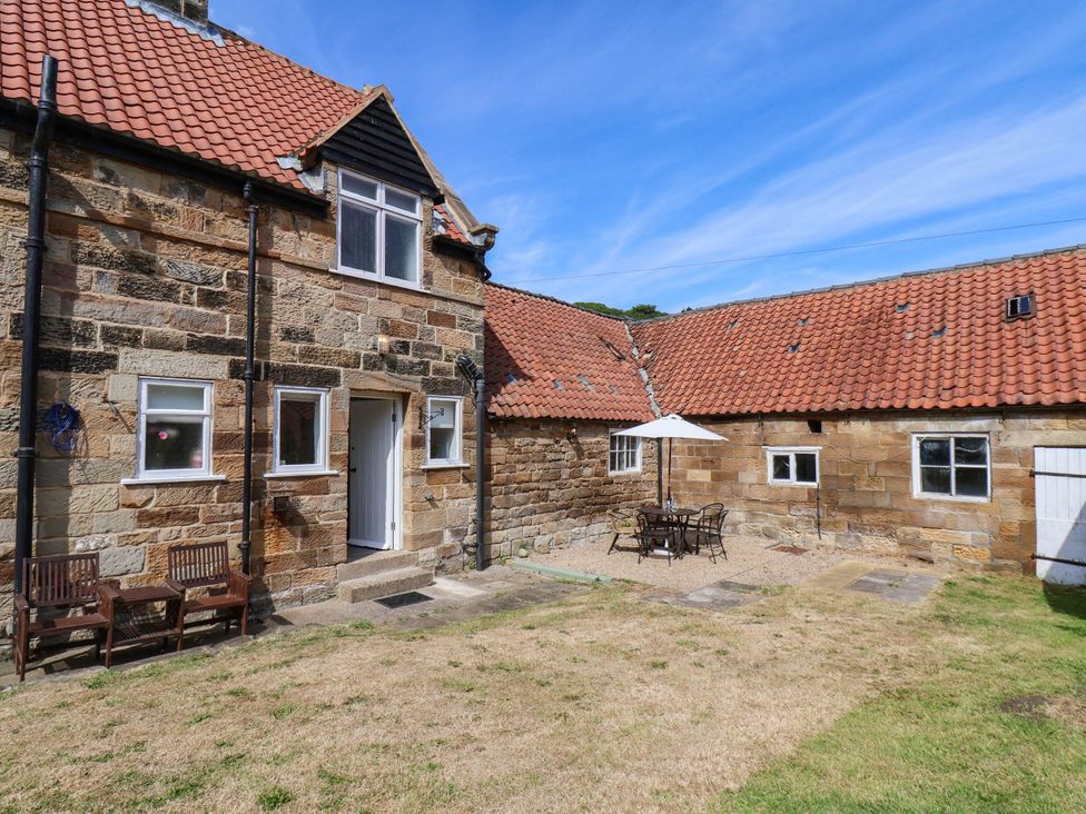 A garden with a table and chairs under an umbrella at Farmhouse Whitby
