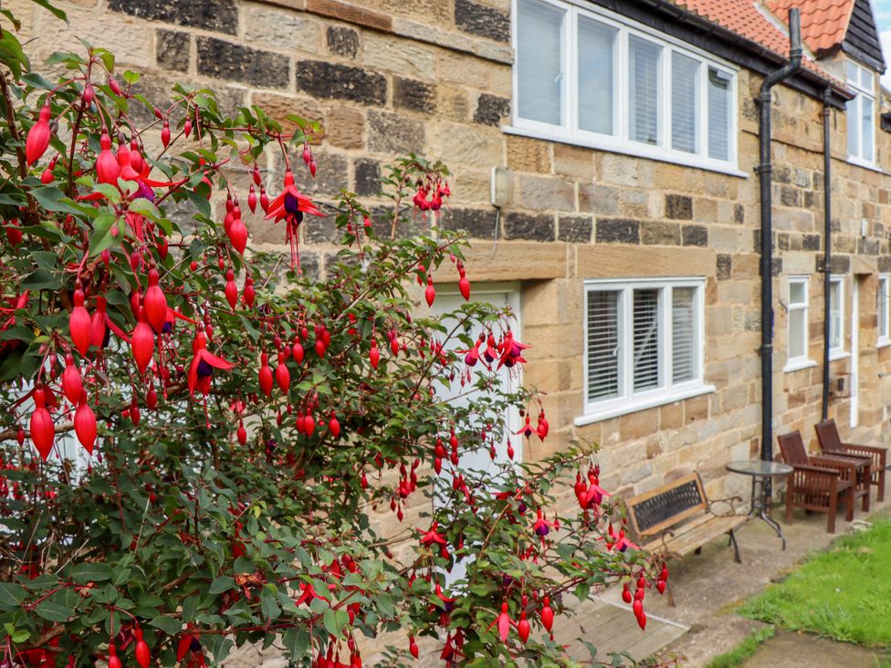 A garden with fuchsia flowers and stone wall at Ewe Cote Hall Farmhouse in Whitby