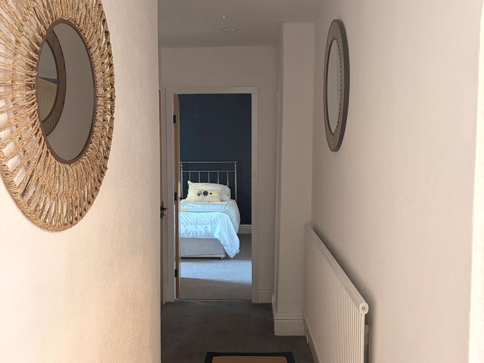 A hallway with mirrors and an open door leading to a bedroom at The Brew House in Bakewell