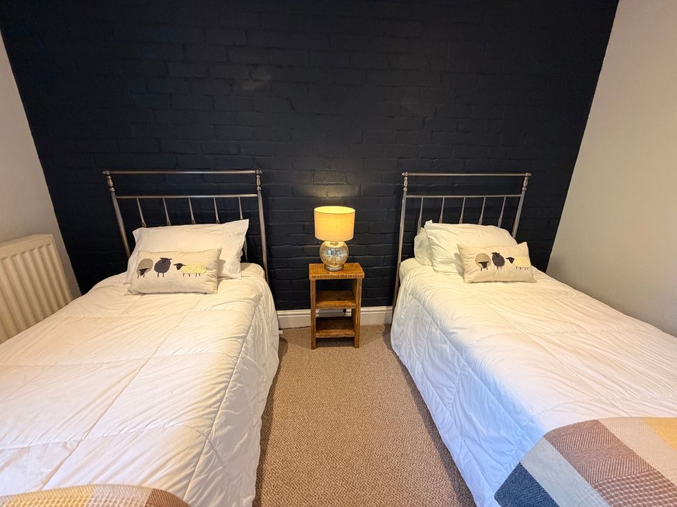 A bedroom with two beds and a nightstand at The Brew House in Bakewell