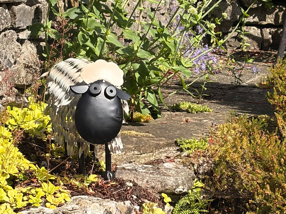 A sheep sculpture among plants and stones in a garden at The Brew House in Bakewell