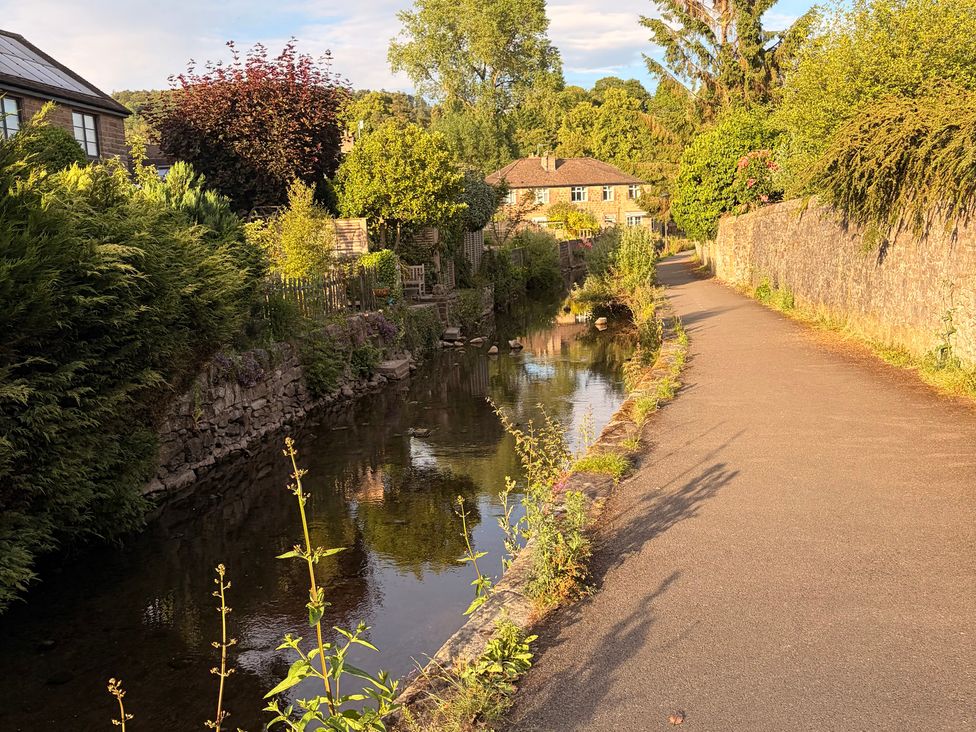 A pathway alongside a canal with trees and houses at The Brew House in Bakewell