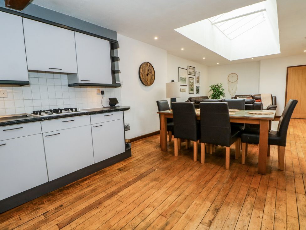A dining room with a kitchen area featuring a table and chairs at The Brew House in Bakewell