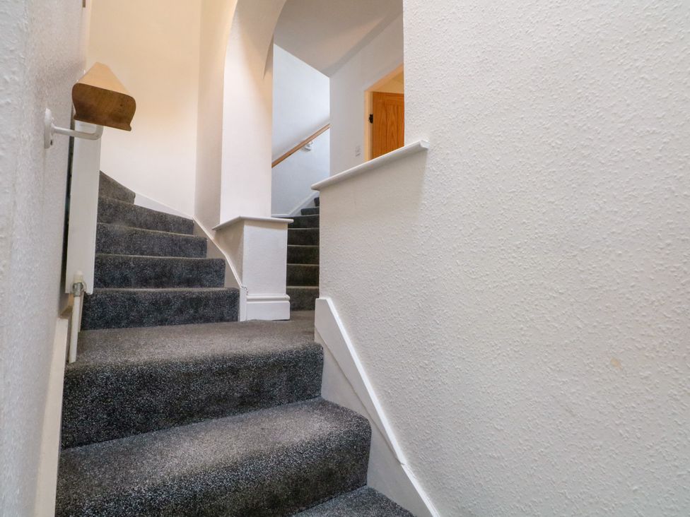 A stairway with grey carpet and a wooden handrail at The Brew House in Bakewell