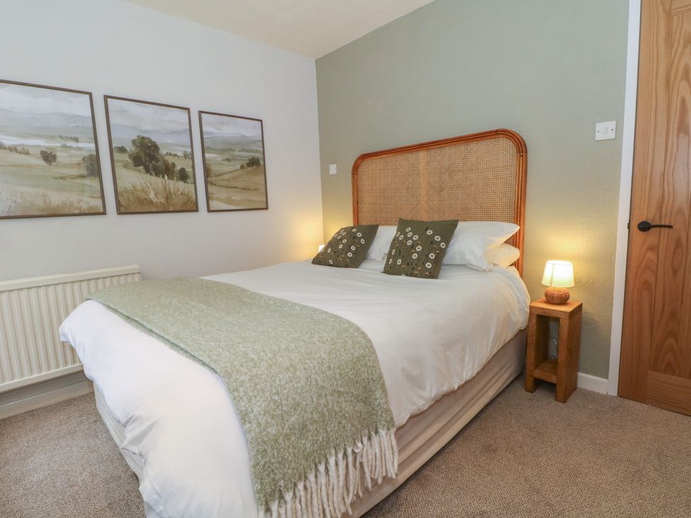 A bedroom with a bed, bedside table and wall art at The Brew House in Bakewell